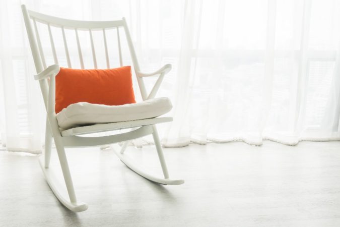 Fauteuil à bascule blanc avec coussin orange dans intérieur minimaliste, alternative élégante à la chaise pliante traditionnelle