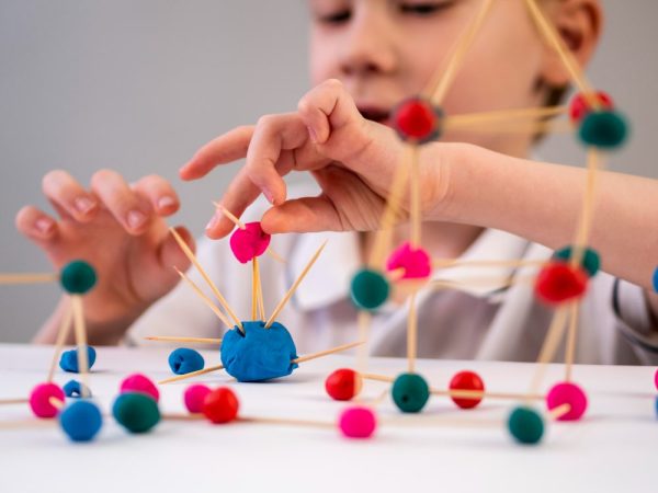 Un enfant concentré, manipulant des perles colorées dans un cadre Montessori, illustrant un atelier d'apprentissage pratique