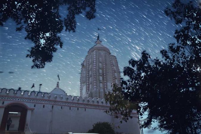 Photographie nocturne d'un temple avec traînées d'étoiles dans le ciel