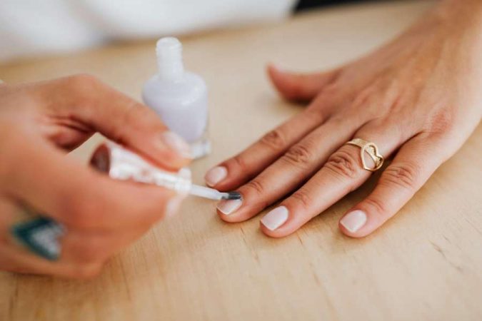 Une personne applique du vernis pour prendre soin de ses ongles.