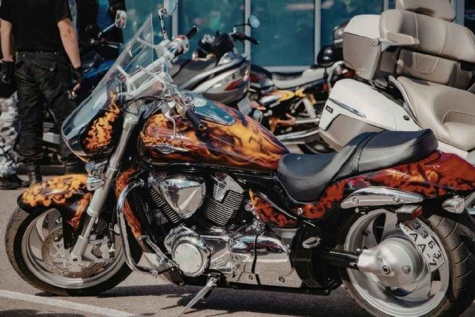 Une moto customisée avec des flammes peintes et son pare-brise de rechange transparent.
